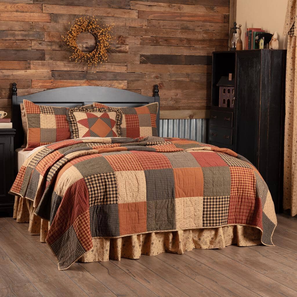Bed with a patchwork quilt, shams, and pillow on it in a rustic room setting