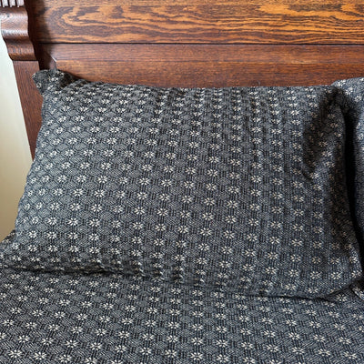 A black and tan pillow sham with a pattern of small star-like shapes - Primitive Star Quilt Shop
