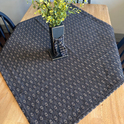 A table with a black and tan table cloth with small star-like patterns - Primitive Star Quilt Shop