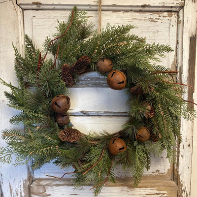 Christmas wreath with pine cones and bells on a rustic wooden door